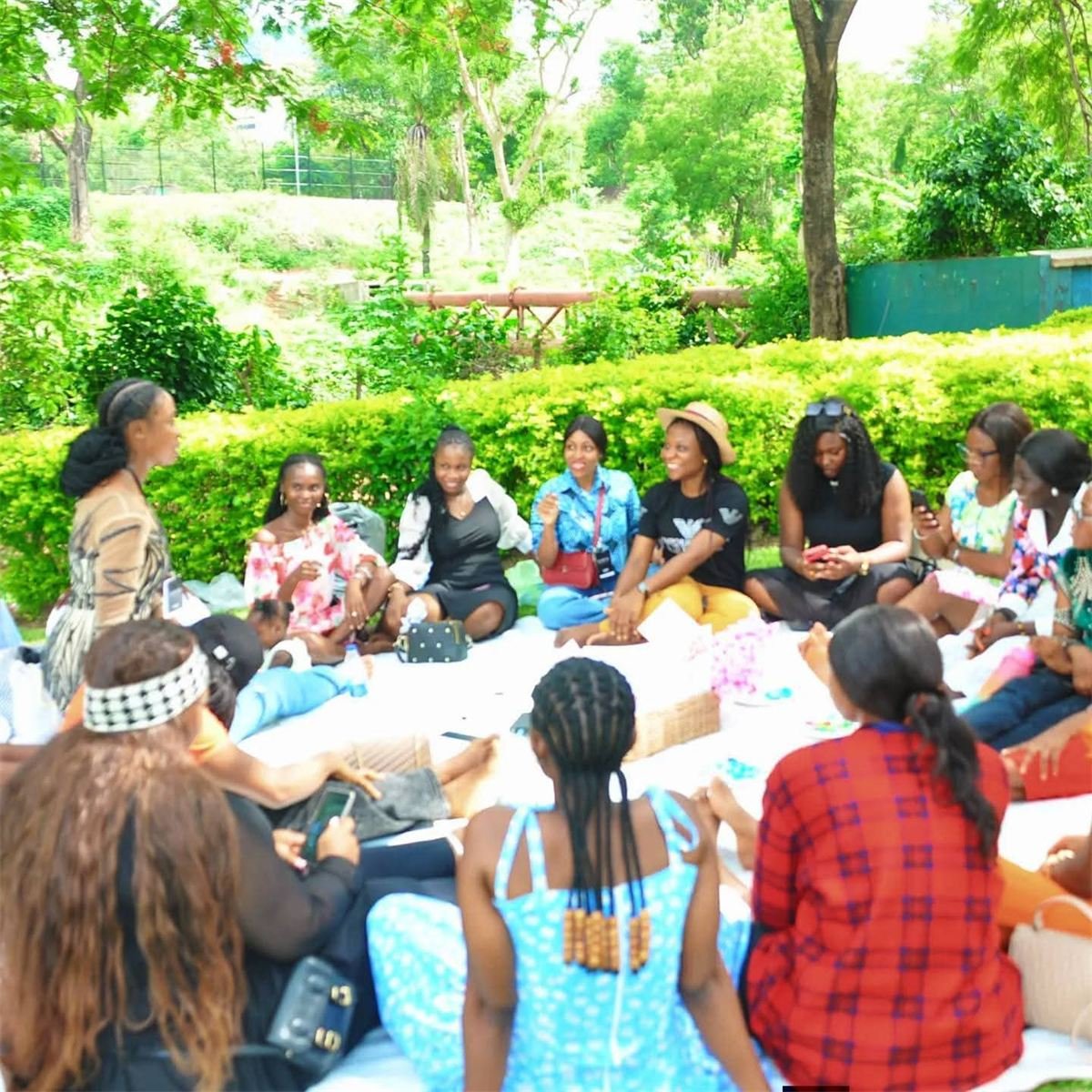 A group of young women sitting in a circle in a garden during a mentorship gathering