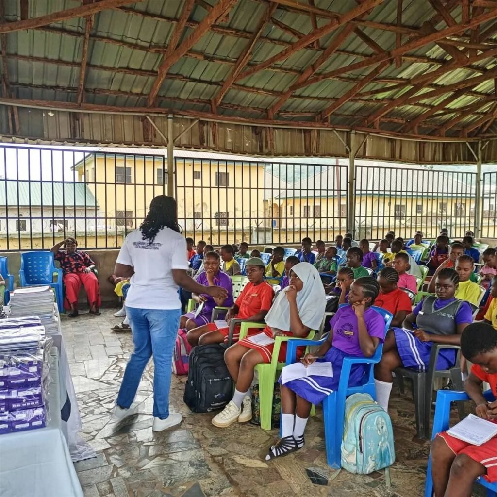 Counselor Deborah Baba addressing students seated in an open school pavilion